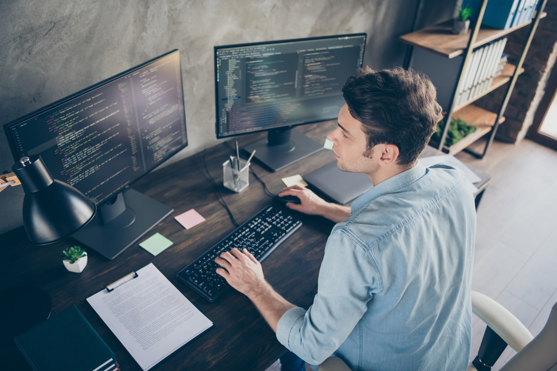 Man working on desk with multiple monitors